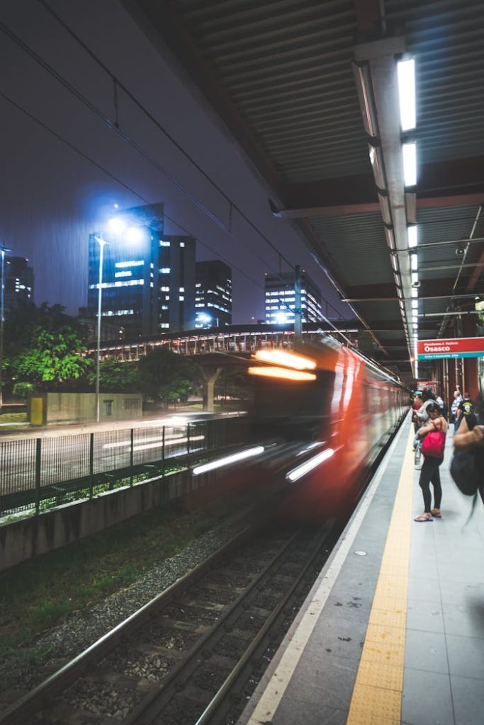Long exposure capturing speed and motion of a train in an urban night setting with light streaks.
